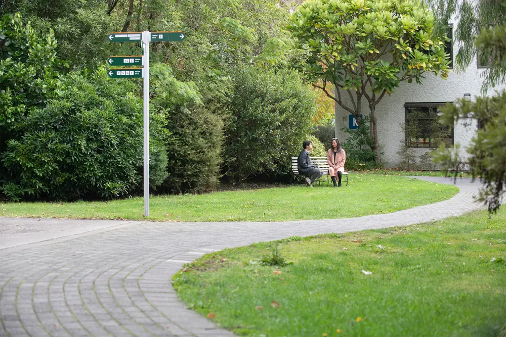 2024 April Naomi and Gio on bench campus signs 
